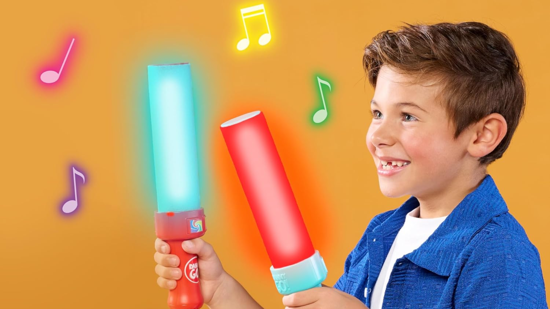 Boy smiling and holding two light-up Danny Go! Color Beat Drumsticks, one glowing red and one glowing teal