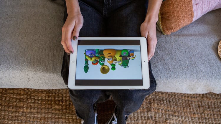 Child sitting on a couch holding a tablet and watching colorful animated kids’ streaming content at home. Yippee is a Christian alternative to Paramount and Paramount+.