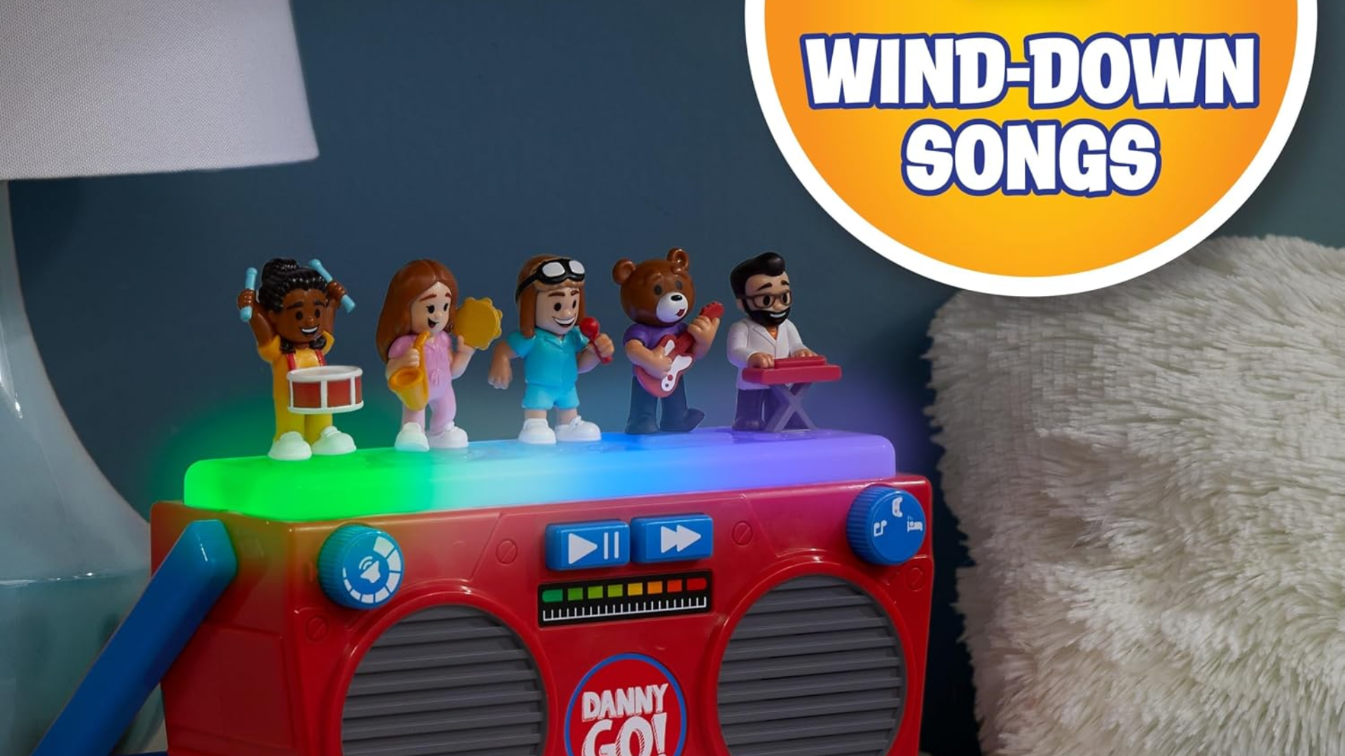Danny Go! Music Mix-Up Boombox glowing with colorful lights on a nightstand in a bedroom, with character figures on top and a badge noting 2 wind-down songs for Bedtime Mode